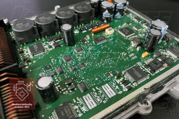 Detailný pohľad na otvorenú dosku plošných spojov riadiacej jednotky motora (ECU) počas repasu v laboratóriu MTE